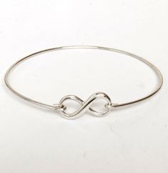 "This is a small sized dainty & delicate sterling infinity which I transform into an infinity bangle bracelet with sterling silver bangle band. PURITY OF METAL: This makes a great gift for teen girls since all elements of the bracelet are sterling silver. Sterling silver is suggested for teen girl jewelry because of the purity of the metal. It's great for adults too. PERSONALIZED OPTIONS: Select optional initial charms (up to 3) to dangle from the infinity loop. I can also add charms to the Minimalist Infinity Bracelets For Gifts, Minimalist Infinity Bracelet For Gift, Elegant Adjustable Sterling Silver Bracelet For Mother's Day, Minimalist Infinity Bracelets As Gift, Minimalist Infinity Bracelet As A Gift, Sterling Silver Infinity Bracelets For Everyday, Sterling Silver Infinity Bracelet For Everyday, Adjustable Dainty Bangle, Nickel-free Sterling Silver Bracelet As Gift