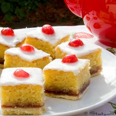 several pieces of cake with white frosting and cherries on top sitting on a plate