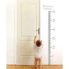 a baby standing in front of a growth chart wall decal