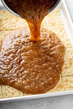 a person pouring sauce on top of crackers