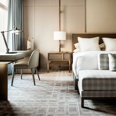 a hotel room with a bed, desk and chair in front of a large window