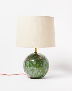 a green lamp sitting on top of a table next to a white lampshade