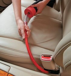 a person using a vacuum to clean a car seat