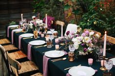 the table is set with purple and white flowers, candles, and plates on it