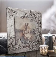 a photo frame with a rabbit on it next to two cups and a teapot