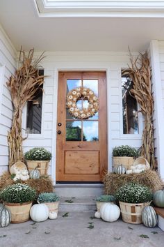 the front door is decorated for fall with pumpkins and gourds in baskets