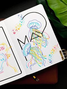 an open notebook with jellyfish on it and the word mom written in rainbow ink