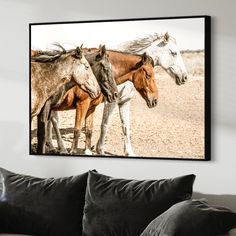 two horses standing next to each other on a wall above a couch in a living room