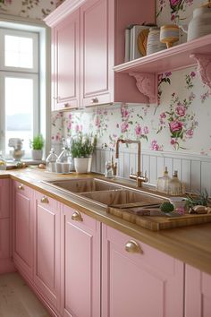 a kitchen with pink cabinets and flowers on the wall behind the sink is filled with dishes