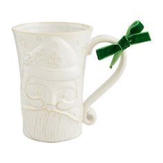 a white ceramic mug with a green bow on the handle and an image of a man's face