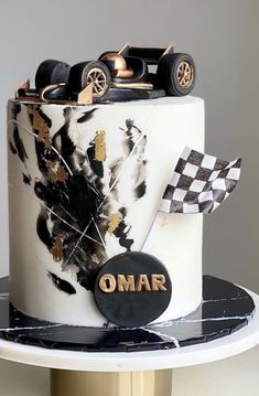 a white cake with black and gold decorations on it's side, topped with a racing car