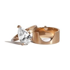 two gold wedding rings with a pear shaped diamond