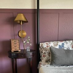 a bed room with a neatly made bed next to a night stand and a lamp