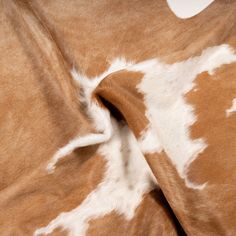 a cow print fabric with white spots on it's back and brown, tan and white fur