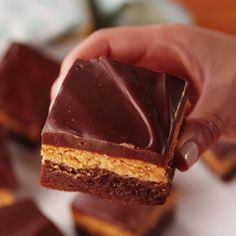 a hand holding a piece of chocolate and peanut butter bars