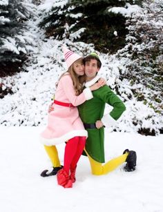 a man and woman in elf costumes posing for a photo on the snow covered ground