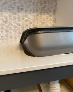 a close up of a sink on a counter top with hexagonal tiles in the background