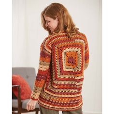 a woman standing in front of a chair wearing a crocheted sweater