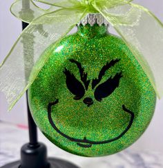 a green ornament with a smiling face painted on it's side and a bow