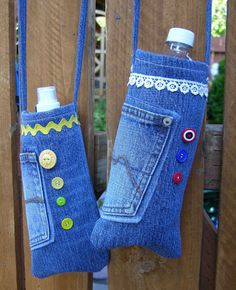 two blue jeans with buttons and lace on them hanging from a wooden fence next to a bottle