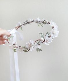 a hand holding a flower crown with white flowers