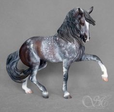 a toy horse is standing on its hind legs and it's body painted gray with white spots