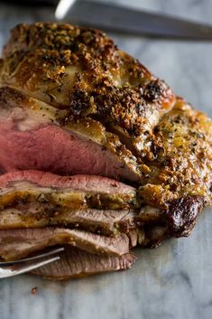 a piece of roast beef on a plate with a knife and fork next to it