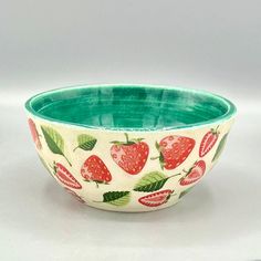 a green and white bowl with strawberries printed on the bottom, sitting on a table