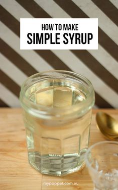 a jar filled with liquid sitting on top of a wooden table next to a spoon