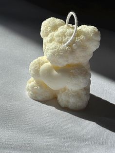 a white teddy bear sitting on top of a gray cloth covered floor next to a window