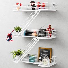 two white shelves with spiderman figurines on top and plants in the bottom