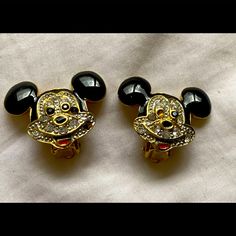 two black and gold mickey mouse ear clips with crystal stones on them, sitting next to each other