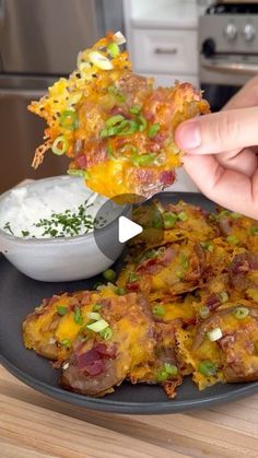 a person is dipping some food into a bowl with ranch dressing on the side and another dish in the background