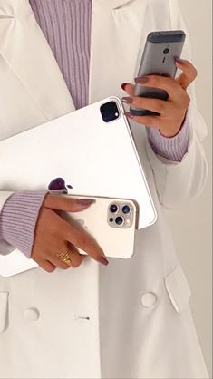 a woman in a white coat holding two cell phones