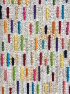 a multicolored wall hanging on the side of a white building with lots of different colored toothbrushes attached to it