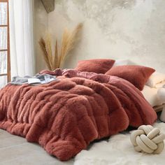 a bed covered in pink fluffy blankets and pillows