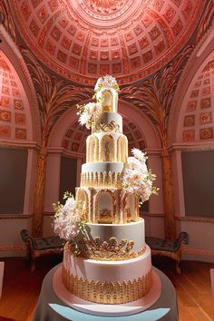 a wedding cake is displayed in an ornately decorated room with pink and gold decorations