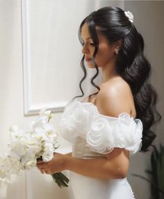 a woman in a wedding dress holding a bouquet of flowers and looking at the mirror