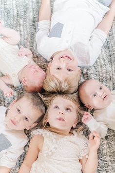 four children laying on the floor with their hands in each other's pockets and looking up at the camera