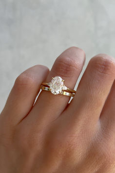 a woman's hand with a gold ring and a white diamond on the finger