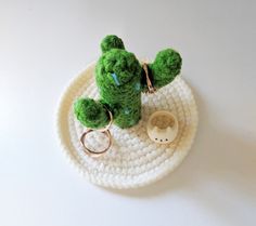 a crocheted cactus keychain sitting on top of a white plate with a ring