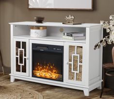 a white entertainment center with a fire in the fireplace