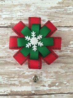 a red and green bow with white snowflake on it, sitting on a wooden surface