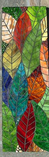 a piece of art made out of stained glass with leaves on the bottom and bottom