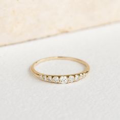 a yellow gold ring with five diamonds on the top and bottom, sitting on a white surface