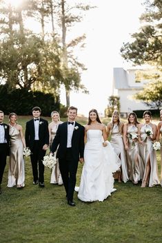 a bride and groom walking with their bridal party