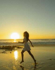 a girl running on the beach at sunset