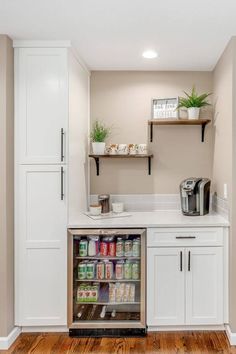 an open refrigerator in a kitchen with white cabinets and wood flooring on the side