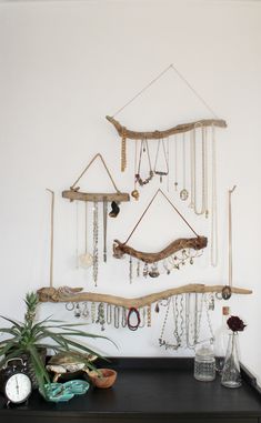 there is a wall hanging made out of branches and jewelry on the shelf next to it