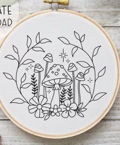 a cross stitch pattern with mushrooms and flowers in the center on a wooden table next to scissors